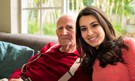 a smiling female aide with an elderly man smiling