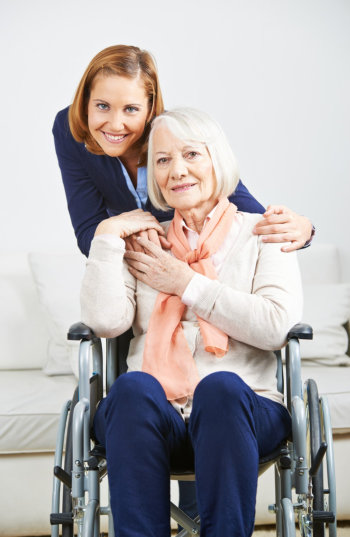 female aide hugging an elderly woman in wheelchair