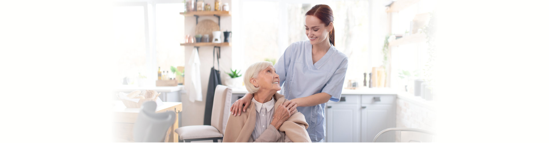 female aide putting a blanket over an elderly woman in wheelchair