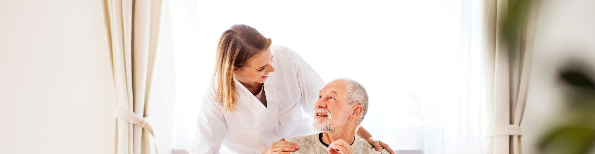 female aide talking to an elderly man in wheelchair