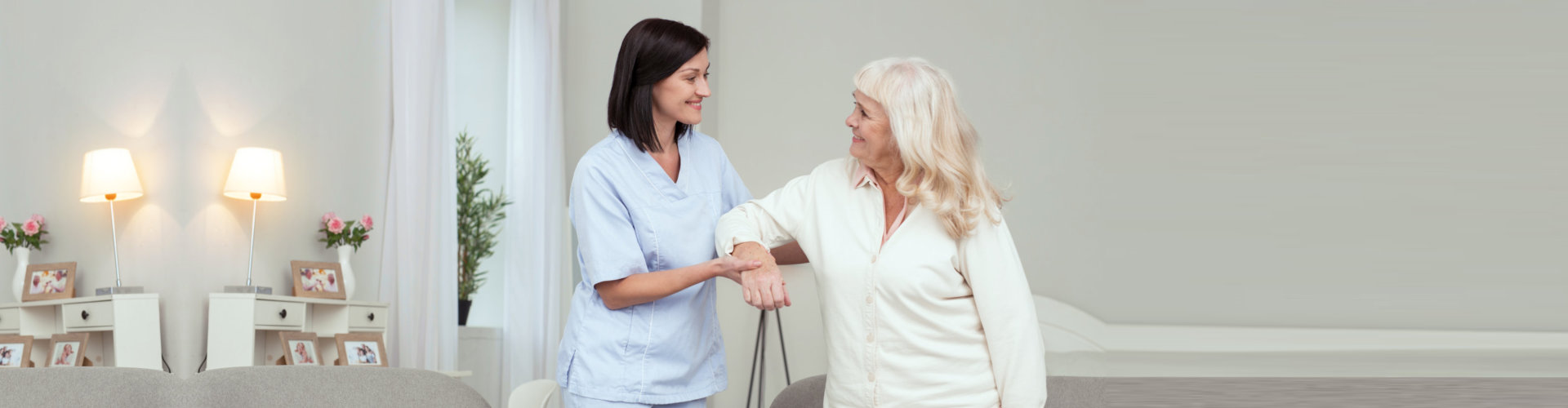 female aide guiding an elderly woman in walking