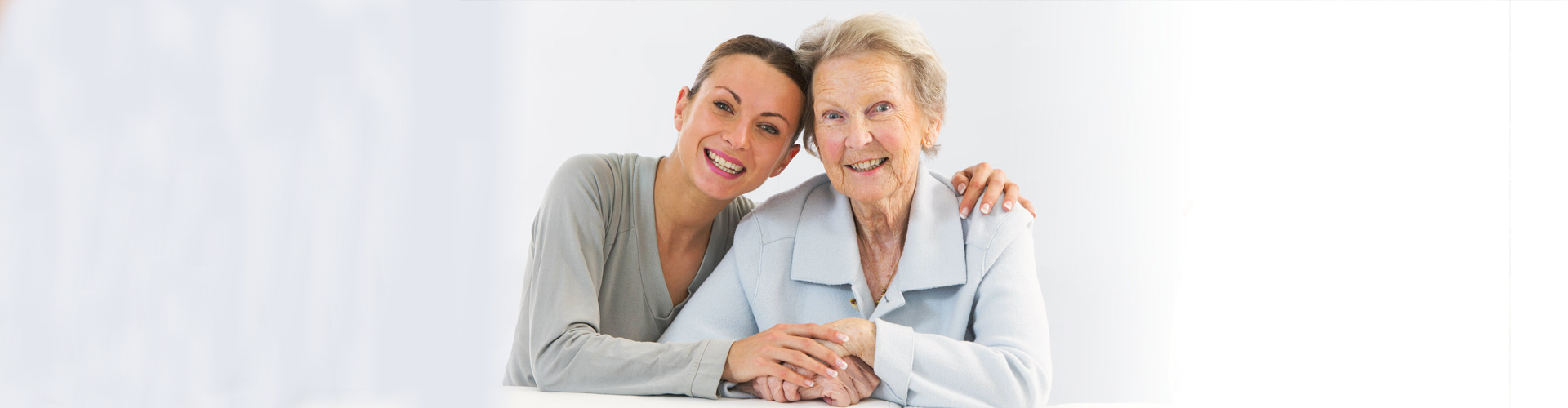 female aide hugging an elderly woman smiling